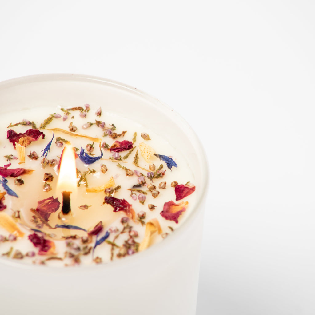 Candle with floral petals on a white background