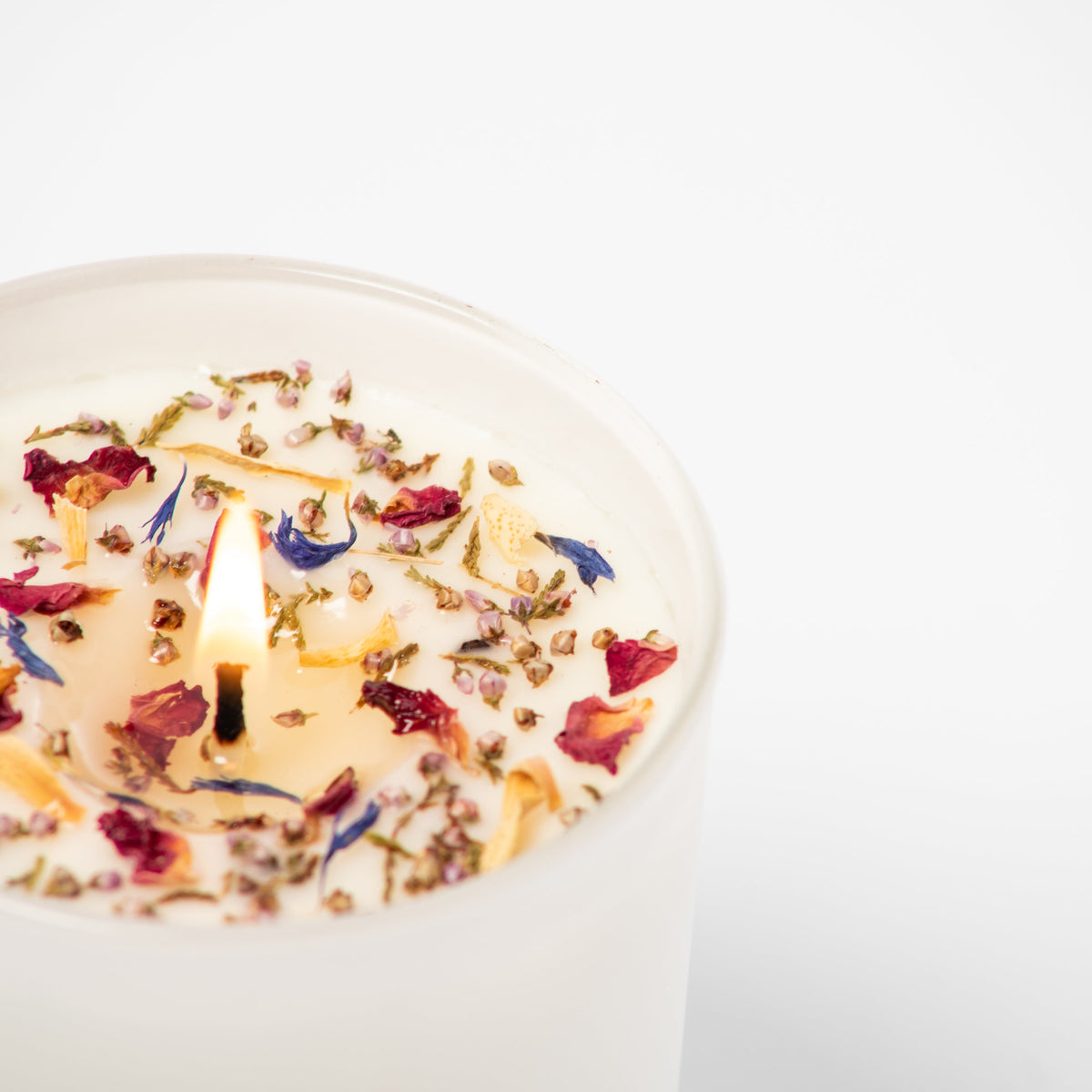 Candle with floral petals on a white background