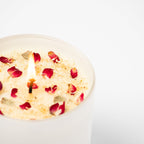 Candle with rose petals in a white dish on a white background