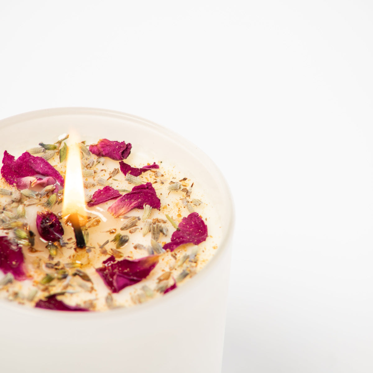 Candle with rose petals on a white background