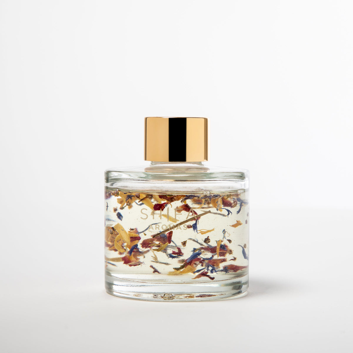 Glass candle with floral design and gold lid on a white background