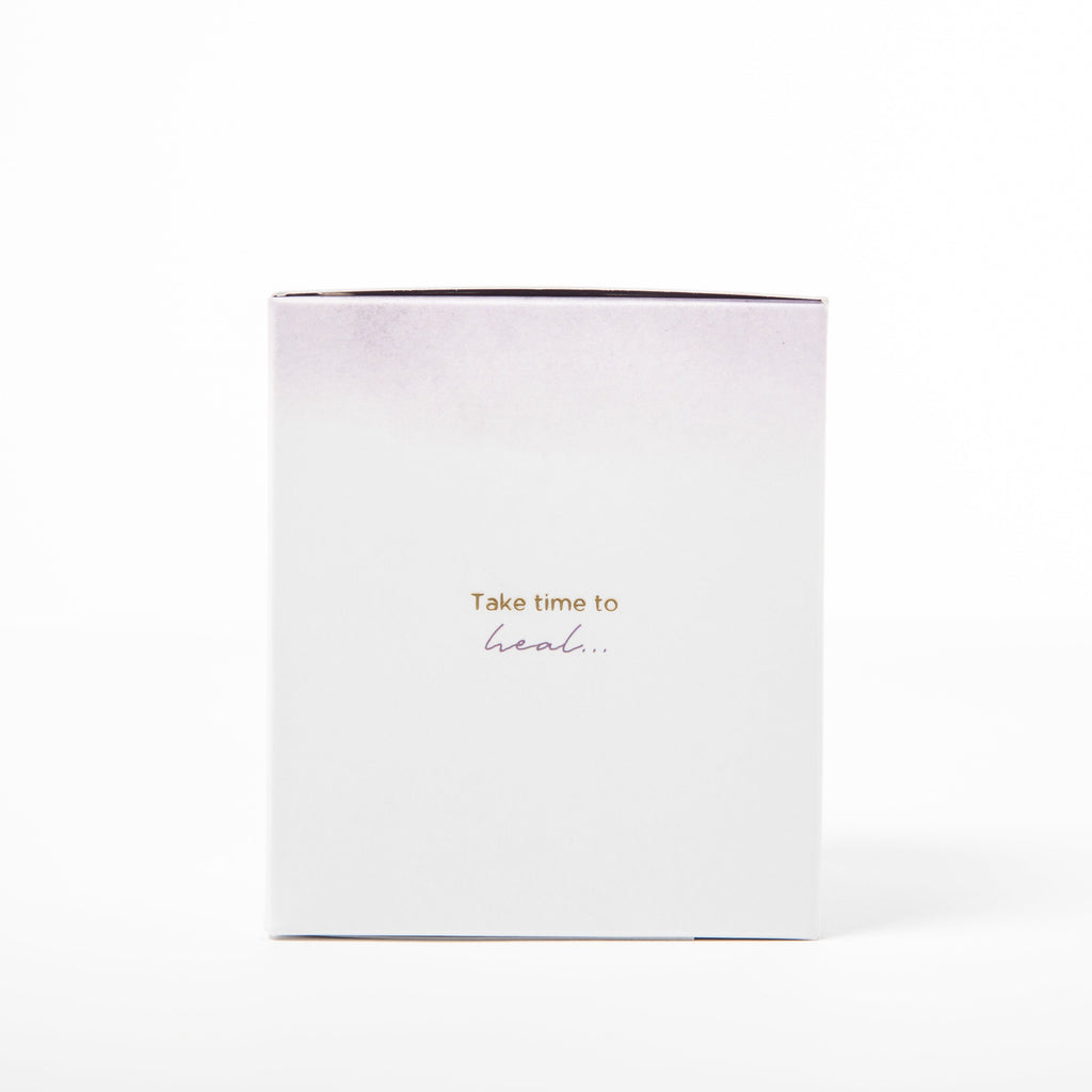 White candle with gold text 'Take time to heal' on a white background