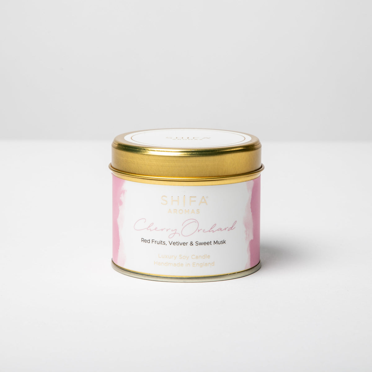 Candle tin with gold lid and white label on a light gray background