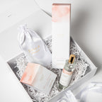 Skincare product set with a bottle, jar, and pouch in a decorative box.
