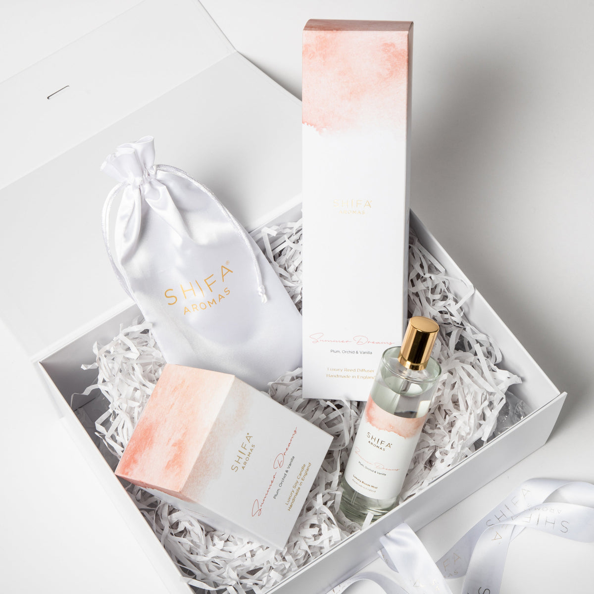 Skincare product set with a bottle, jar, and pouch in a decorative box.