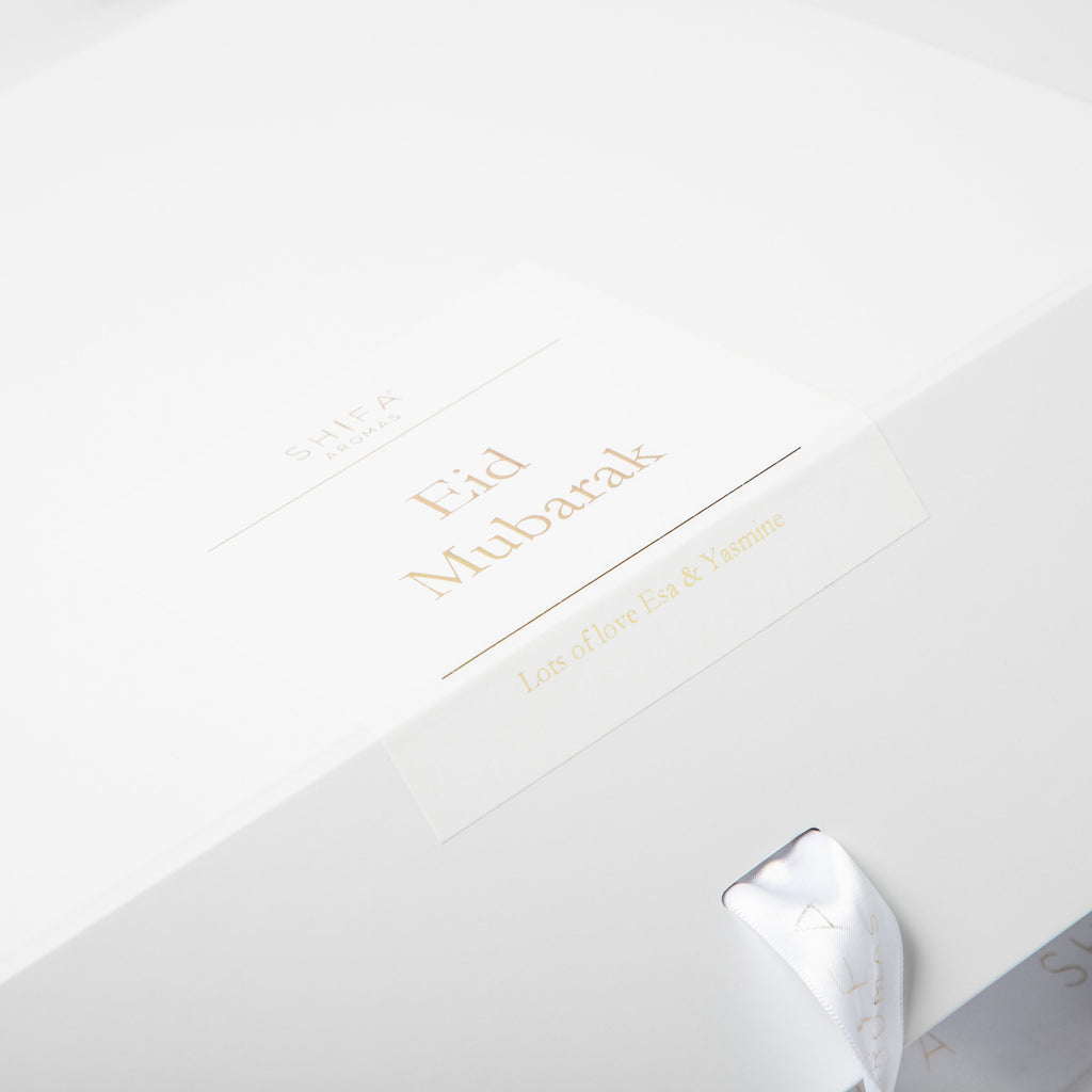 White gift box with gold text and a silver bow on a white background