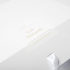 White gift box with gold text and a silver bow on a white background
