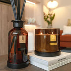 A diffuser and a candle with 'Li' branding on a surface in a home setting.
