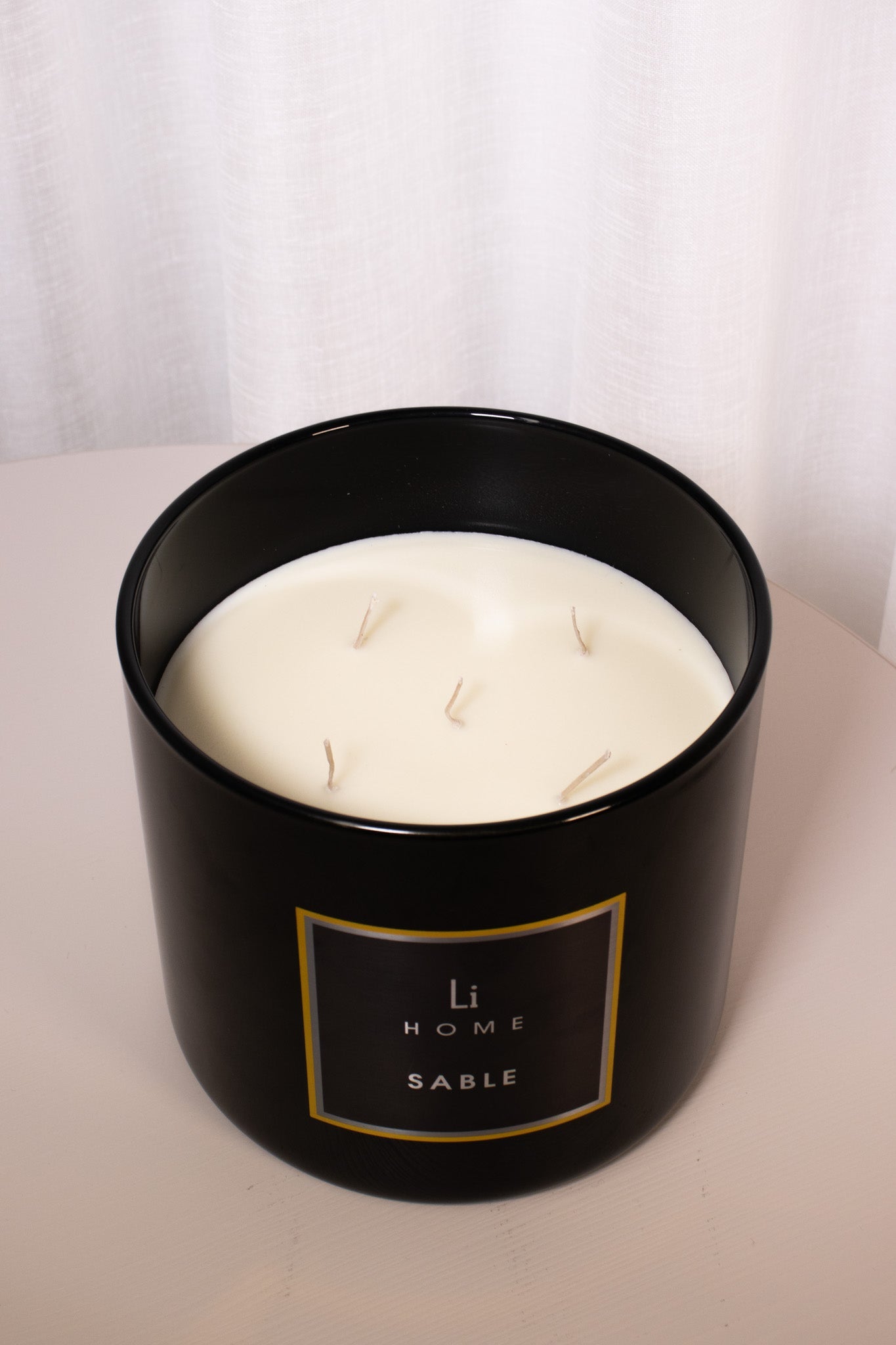 Black container with a white candle labeled 'LI Home Sable' on a light background