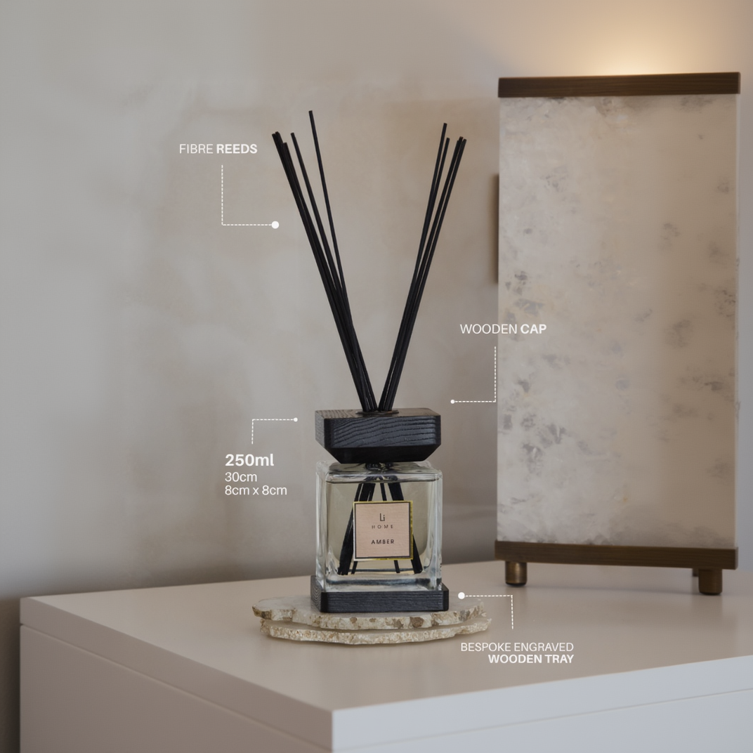 Diffuser with black reeds on a wooden tray against a neutral wall