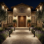 Stately stone house with a well-lit pathway and decorative elements at night.