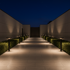 Evening view of a pathway lined with illuminated lamp posts between two walls.