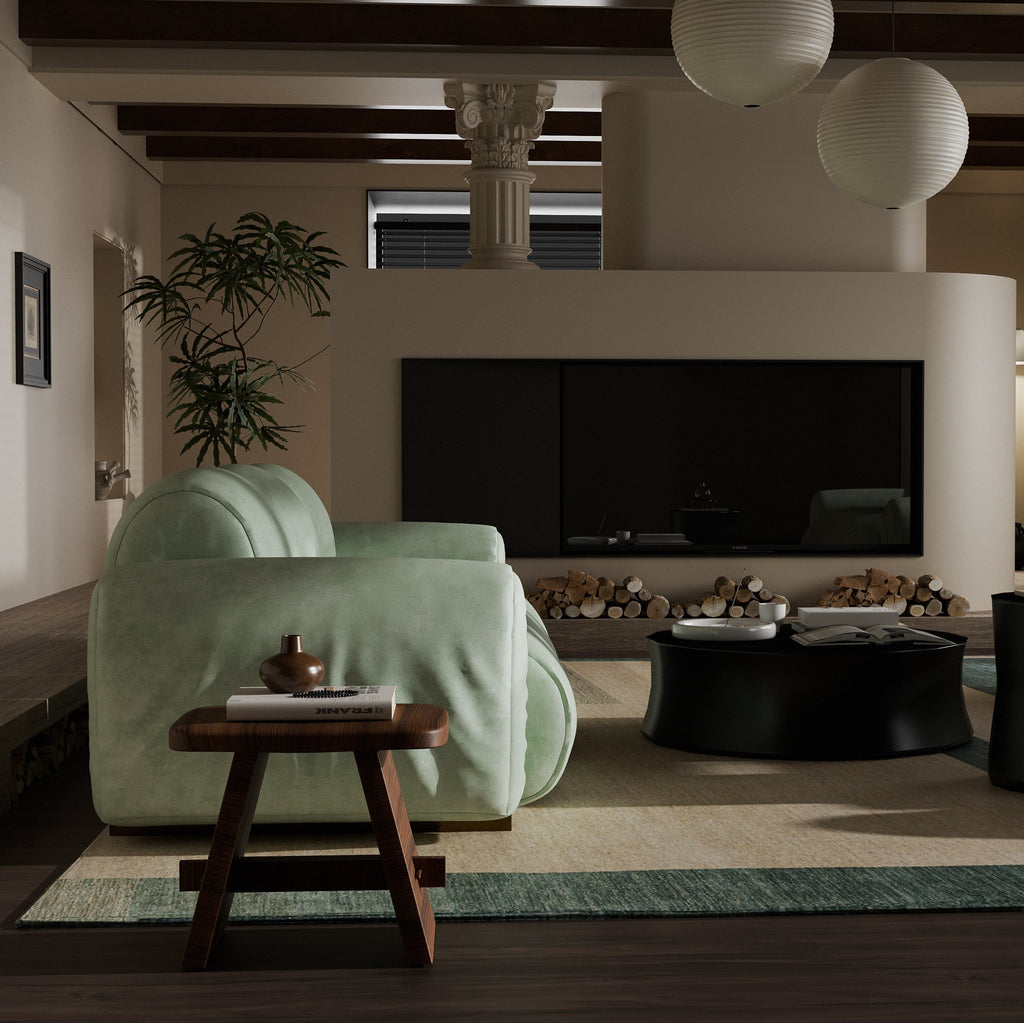 A modern living room featuring a light sage green velvet armchair as the main product, styled in a warm, minimalist interior with a black coffee table, wooden side table, and a fireplace in the background.