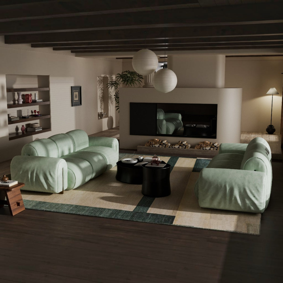 A modern living room featuring two oversized, curved light green sofas arranged on a geometric area rug. The room has dark wood ceiling beams, a built-in fireplace with a black surround, and two white spherical pendant lights hanging above.
