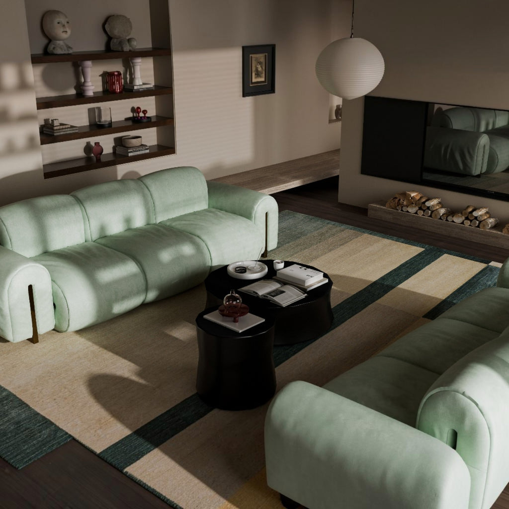 A modern living room featuring a light mint green modular sofa and matching armchair, styled with dark round coffee tables and a striped beige and green area rug.