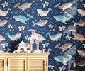 Wallpaper with whale pattern on a blue background, with a wooden cabinet and toys in the foreground.