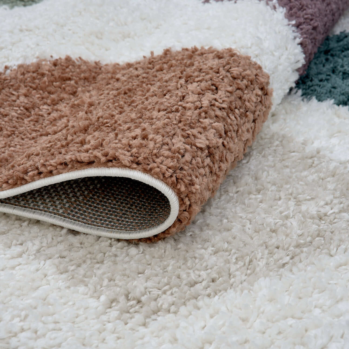 Close-up of a textured rug with a neutral color palette on a light background