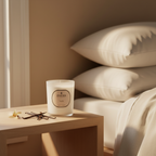 Candle on a bedside table with pillows in the background
