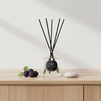 Reed diffuser with black sticks on a wooden surface with a light background