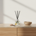 Diffuser with reeds and a bowl on a wooden surface with a neutral background