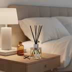 Diffuser with reeds on a nightstand next to a lamp and books in a bedroom setting