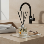 Reed diffuser on a bathroom counter with a black faucet in the background