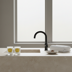 Modern bathroom sink with black faucet, towels, and candles on a neutral background