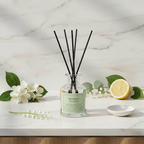 Diffuser with black sticks on a marble surface with flowers and a lemon.