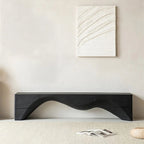 Modern black wavy bench against a neutral wall with abstract art