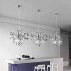 Three modern pendant lights hanging above a kitchen counter with fruit on a white wall background.