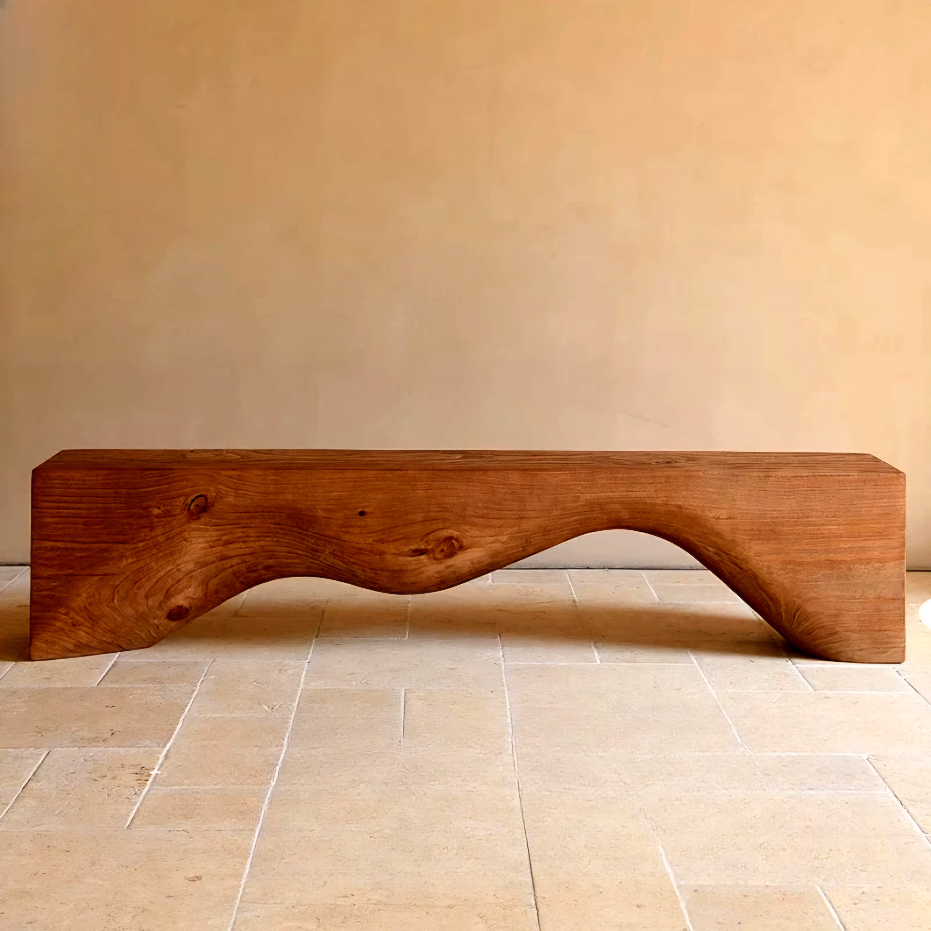 Wooden bench with a wavy design on a tiled floor against a beige wall.