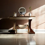 Modern vanity setup with mirror, stool, and decorative items against a neutral wall.