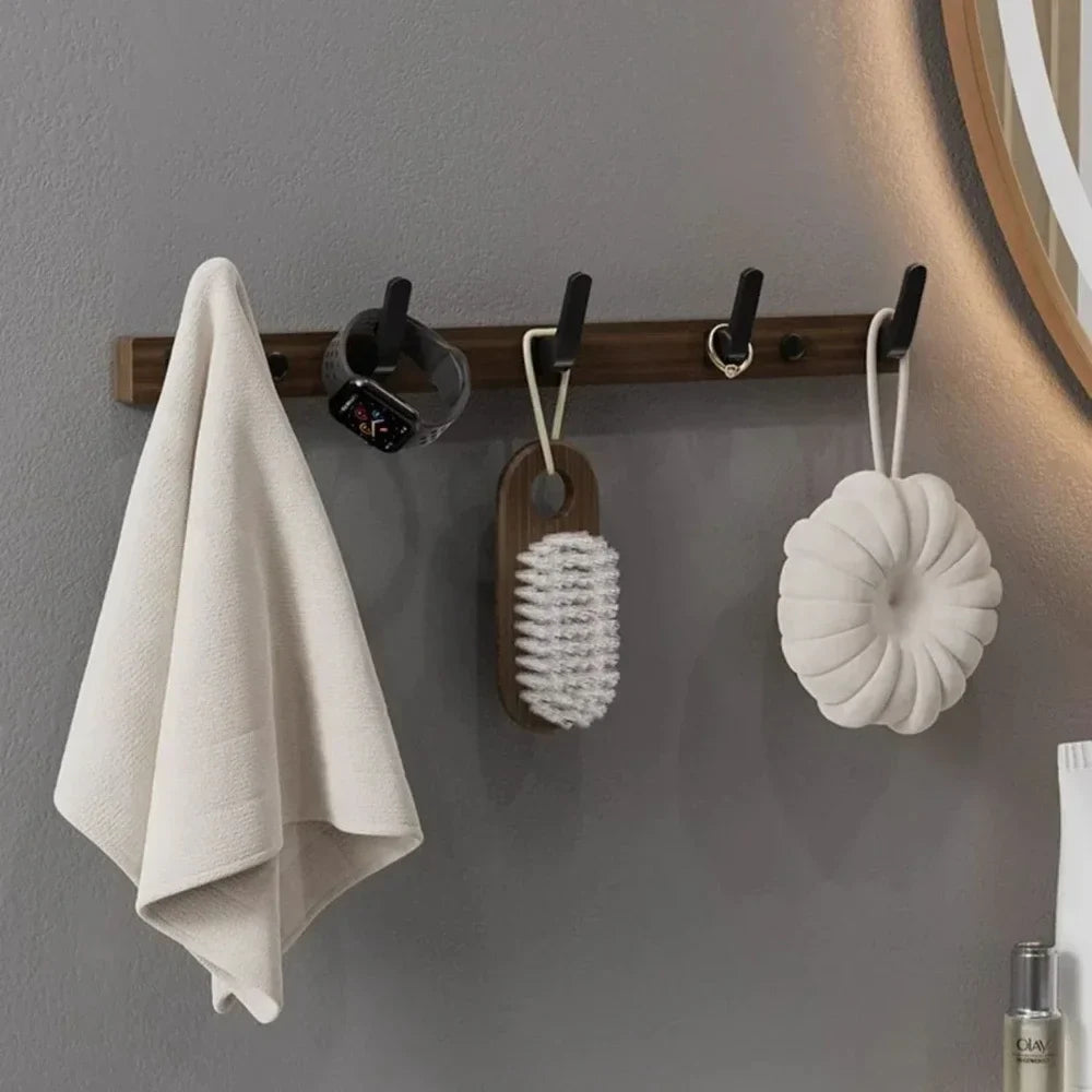 Towel and cleaning tools hanging on a wooden rack against a gray wall.