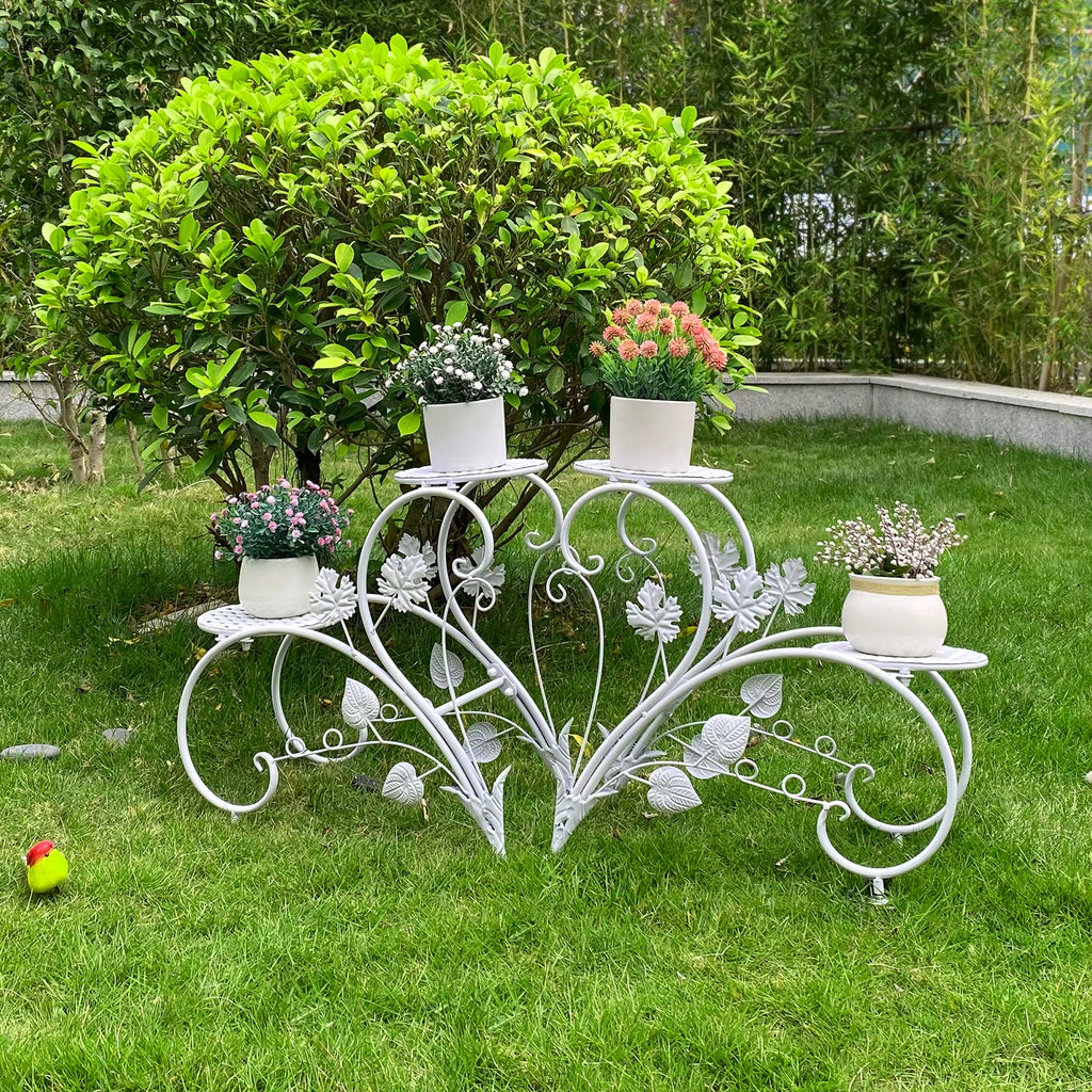 Decorative white metal plant stand with potted plants on a grassy area