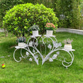 Decorative white metal plant stand with potted plants on a grassy area