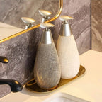 Two decorative bottles on a tray with a mirror and bathroom setting in the background