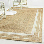 Natural jute rug with a border in a room with white chairs.