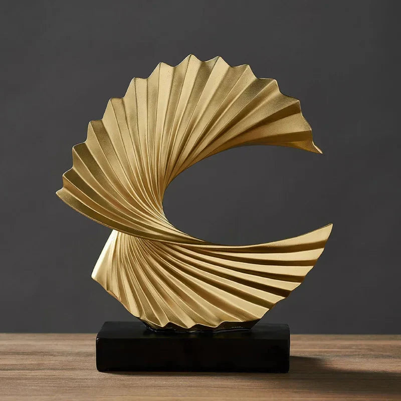 Gold abstract sculpture on a wooden surface with a dark background