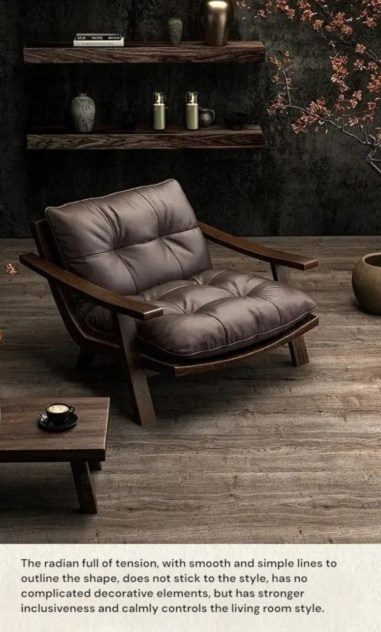 A mid-century modern armchair with a tufted brown leather cushion and dark wood frame, set in a styled living room with wooden floors, floating shelves, and a small side table.