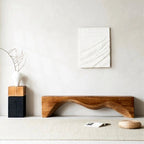 Wooden bench in a minimalistic room with abstract art on the wall.
