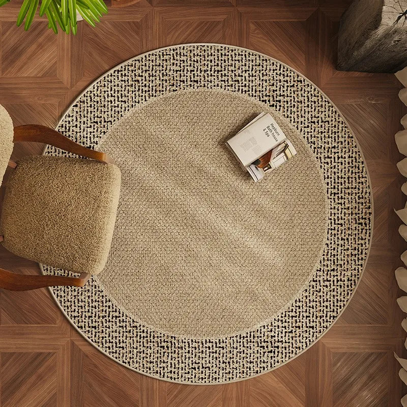 Round beige rug on a wooden floor with a chair and books on top