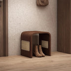 Brown shoe storage bench with shoes underneath against a neutral wall.