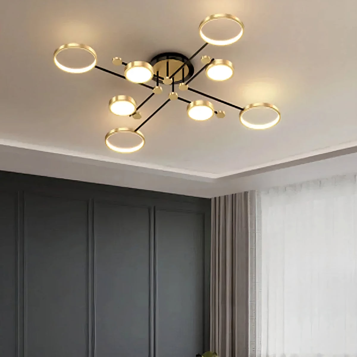 Modern multi-light ceiling fixture with circular gold-rimmed shades and black arms, installed on a white ceiling in a contemporary room with dark gray paneled walls and curtains.