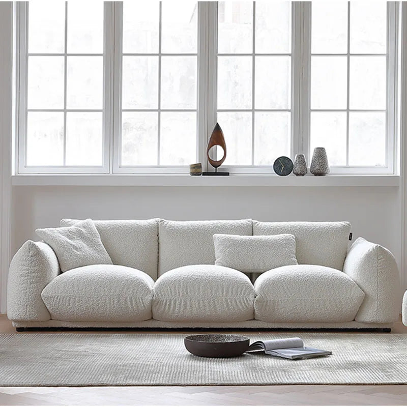 White sofa in a room with large windows and minimal decor.