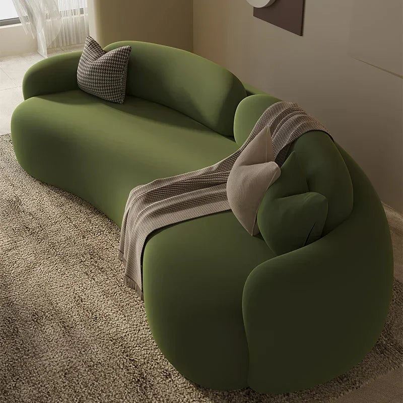 Green sofa with a blanket and pillow in a room with a window and light-colored carpet.