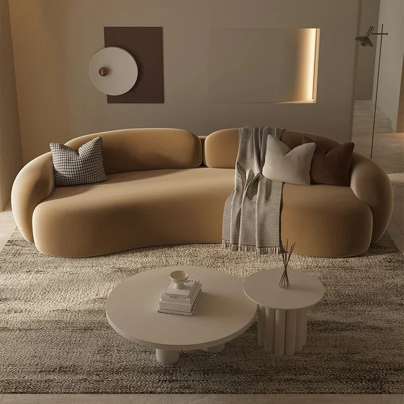 Modern living room with a curved beige sofa, round coffee table, and decorative elements.