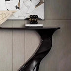 Decorative console table with a unique black leg design against a neutral wall.