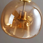 Gold pendant light with a reflective surface on a gray background