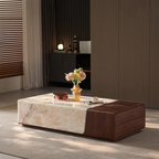 Modern coffee table with marble top and brown leather side in a room setting.
