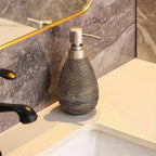 Decorative soap dispenser on a bathroom counter with marble wall and sink in the background